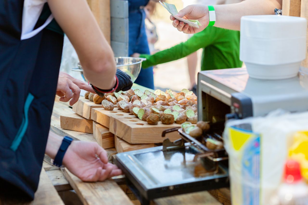 Outdoor market scene showcasing freshly prepared French snails being served to customers.