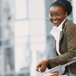 Home Smiling woman with eyeglasses holding a shopping bag outdoors.